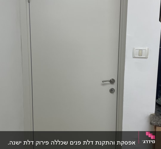 דלת לבנה עם ידית מתכת ומתג חשמל